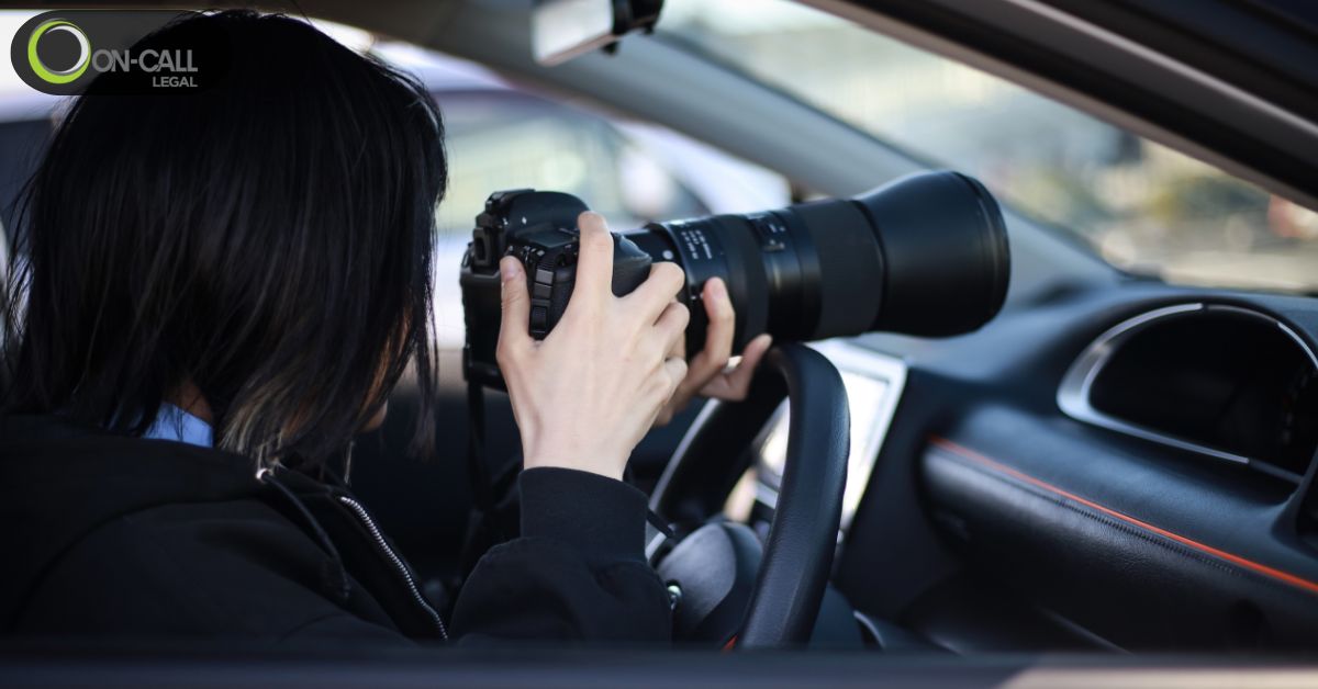 Person in a car photographing with a long telephoto lens during surveillance