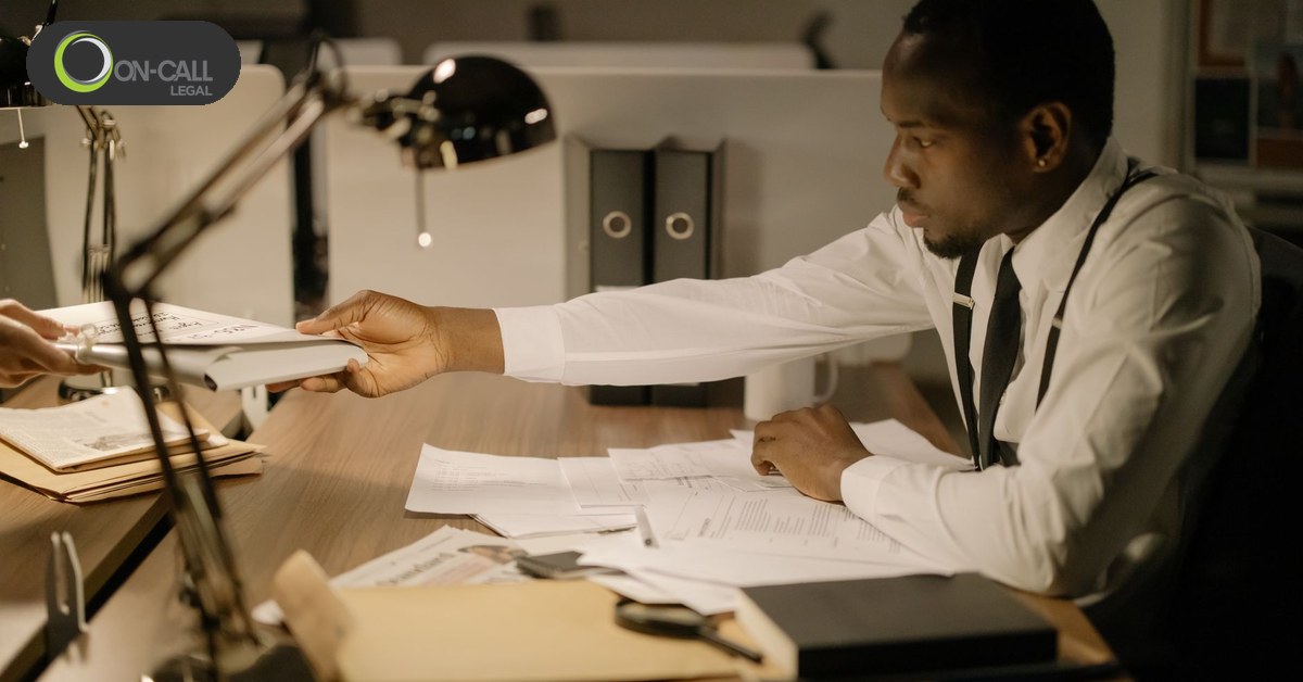 A person handing over a signed document across a desk in an office