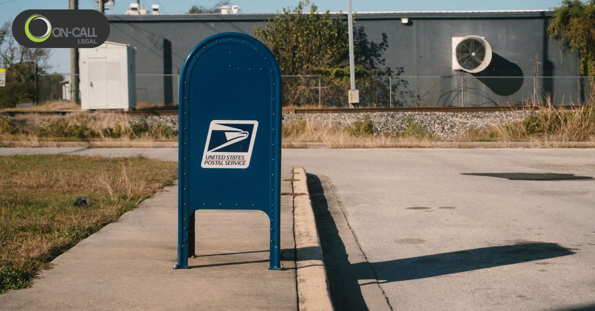 A blue United States Postal Service mailbox on a sidewalk on a sunny day