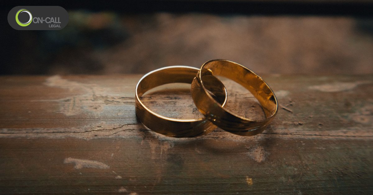 Two gold wedding bands resting together on a worn wooden surface