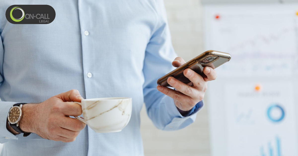 Professional checking an email on a smartphone while holding a cup of coffee