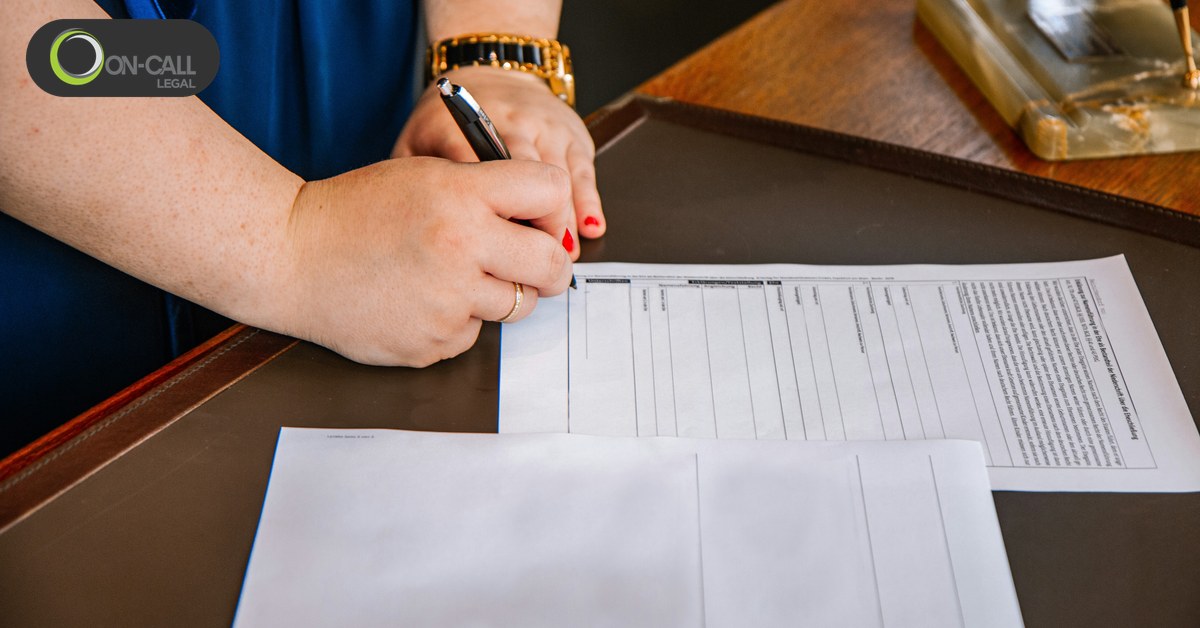 A person filling out paperwork with a pen at a desk