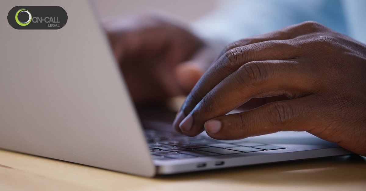 Close-up of hands typing on a laptop keyboard on a wooden desk