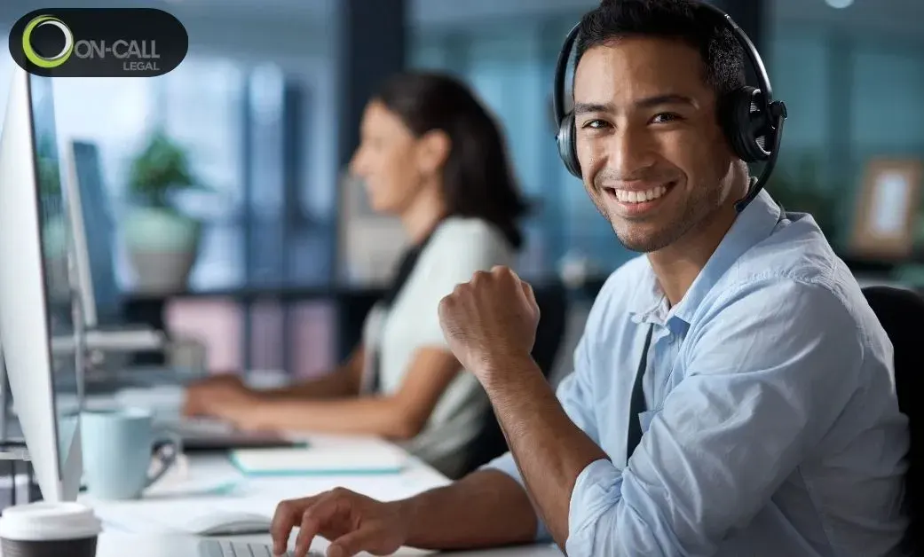 Smiling support agent wearing a headset at a computer in an office